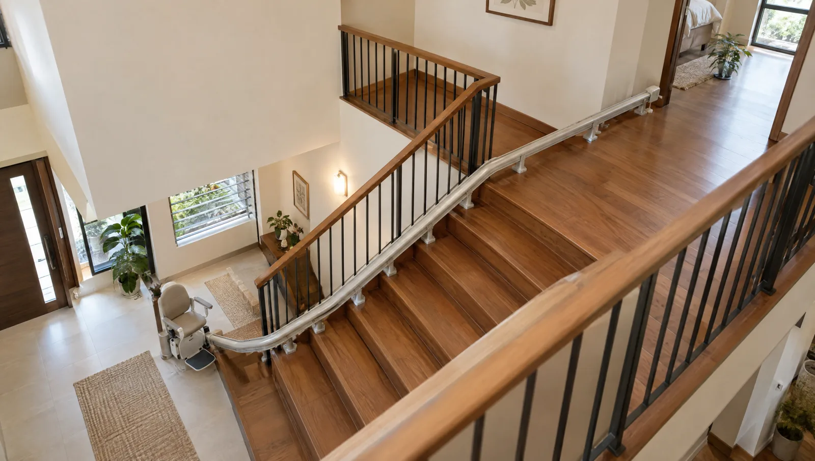 A stairlift rail following a long staircase, with a curved parking extension at the lower landing.