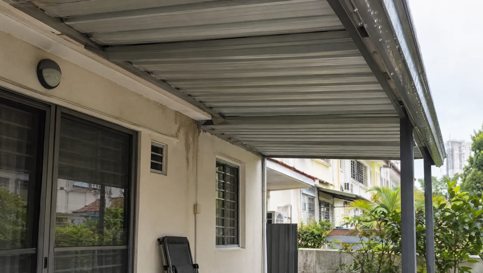 Aluminium patio canopy and wall junction viewed safely from below after rain.