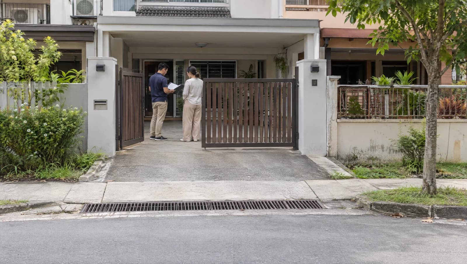 Survey discussion at a landed-home gate showing its posts, driveway and roadside approach.