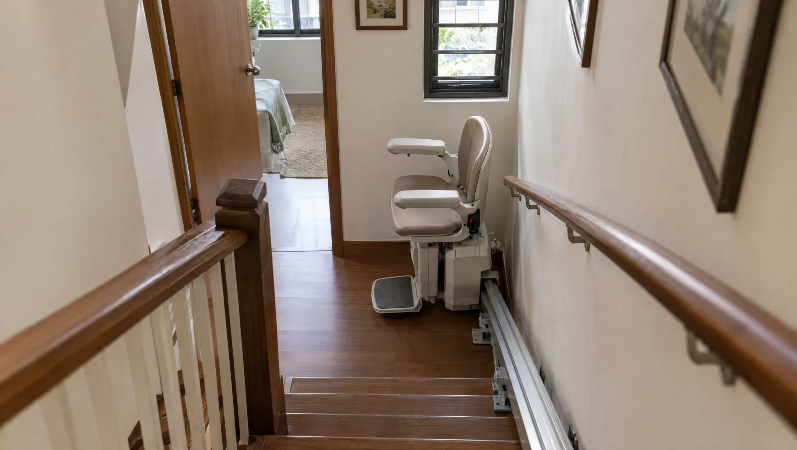 Unfolded stairlift at a compact staircase beside a handrail, newel and doorway.